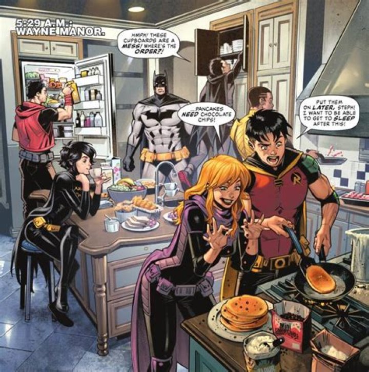 Batman stands stunned speechless in the kitchen doorway as (LtR) Red Hood, Batgirl (Cass), Robin (Damian), Batgirl (Steph), Signal, and Robin (Tim) raid the fridge and cupboards, sip tea, and make pancakes and bacon in Batman #135 (2023). Damian complains that there is no order in the cupboards, while Tim and Steph argue about putting chocolate chips in the pancakes. 