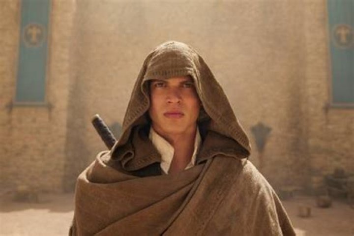 Rand (Josha Stradowski) standing looking resolute and wearing a hood